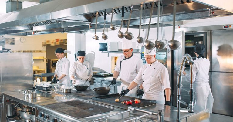 five-chefs-wearing-uniforms-posing-in-a-commercial-kitchen-1024x536