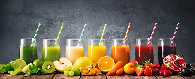 Panoramic food background with assortment of fresh fruits and vegetables juices in rainbow colors